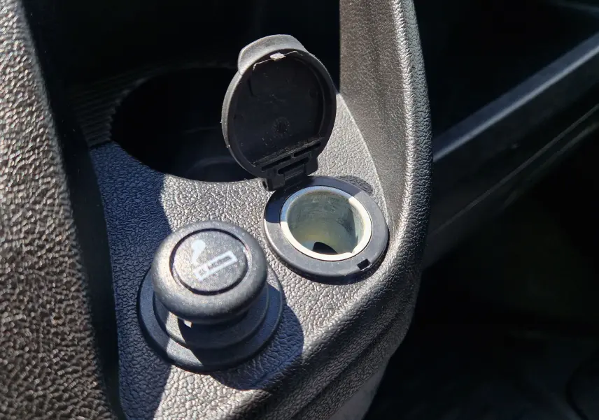 Gros plan sur la prise allume-cigare et son cache ouvert dans l'habitacle du Citroën Jumper blanc.