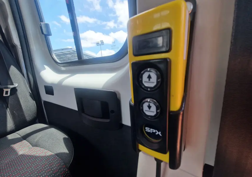 Vue intérieure côté droit de la cabine blanche du Citroën Jumper avec commande jaune pour benne à ridelles grillagées.