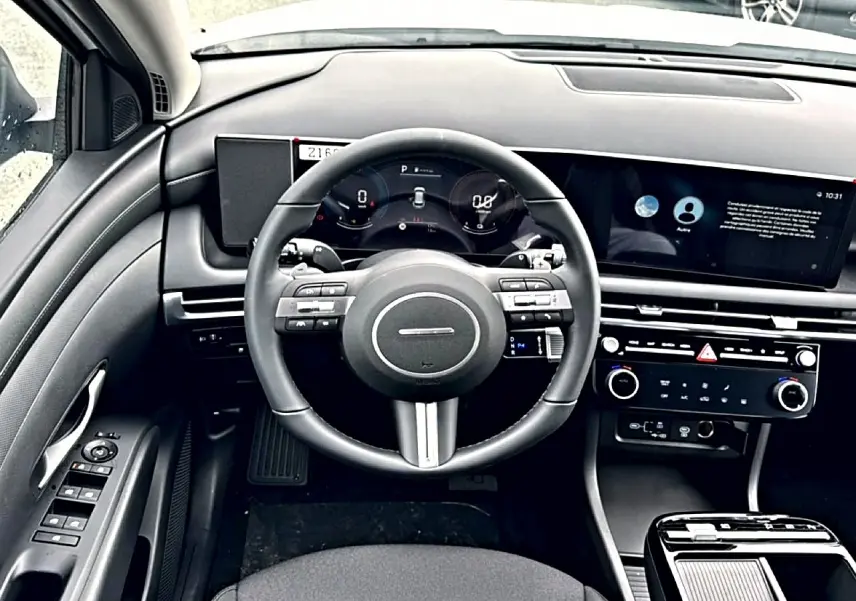 Intérieur noir du Hyundai Tucson 2026, vue frontale du volant cuir multifonction et tableau de bord digital.