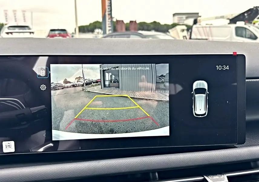 Écran intérieur montrant la caméra de recul du Hyundai Tucson blanc, vue arrière avec lignes de guidage colorées.