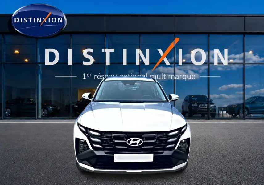 Vue de face du Hyundai Tucson blanc 2026 avec calandre noire distinctive devant une vitrine Distinxion.
