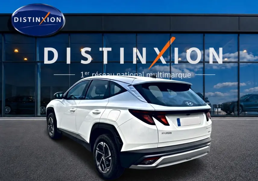Vue 3/4 arrière droite du Hyundai Tucson blanc 2026 hybride, avec jantes alliage et feux arrière LED distinctifs.