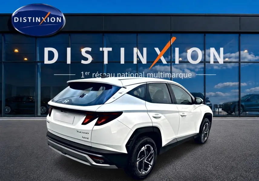 Vue 3/4 arrière droite d'un Hyundai Tucson blanc hybride 2026 avec jantes alliage et feux arrière LED distinctifs.