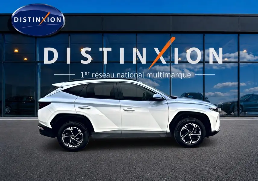 Vue latérale droite d'un Hyundai Tucson blanc 2026 avec jantes alliage 17 pouces devant une vitrine Distinxion.