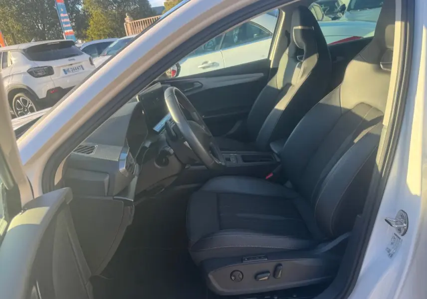 Vue intérieure côté conducteur de la CUPRA Leon Sportstourer blanc 2024, avec sièges sport en cuir noir et tableau de bord moderne.