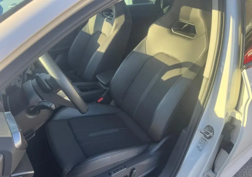 Vue intérieure côté conducteur d'une CUPRA Leon Sportstourer blanche 2024, sièges sport en cuir noir avec surpiqûres.