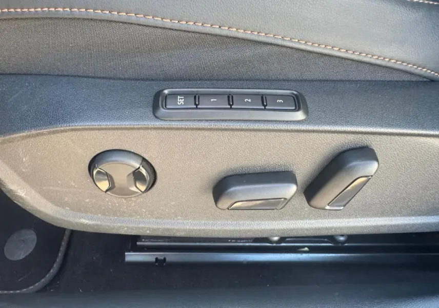 Détail des commandes de réglage électrique des sièges en tissu noir avec surpiqûres contrastantes dans une CUPRA Leon Sportstourer blanche.