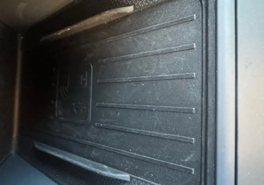 Gros plan sur le tapis de recharge sans fil noir dans l'habitacle du CUPRA Leon Sportstourer blanc 2024.