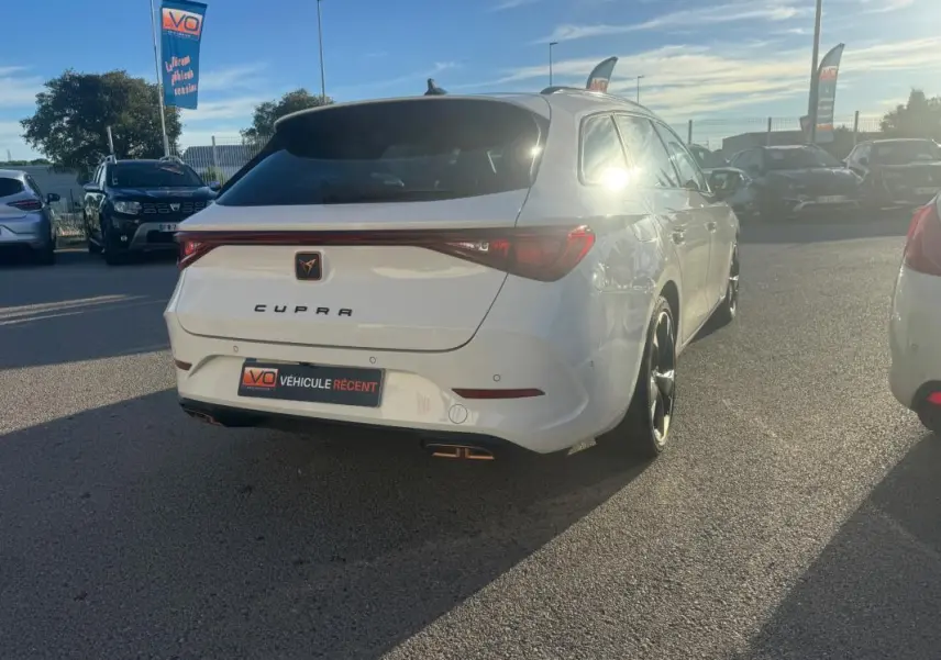 Vue 3/4 arrière droite d'une CUPRA Leon Sportstourer blanche 2024 avec feux arrière reliés et double sortie d'échappement.