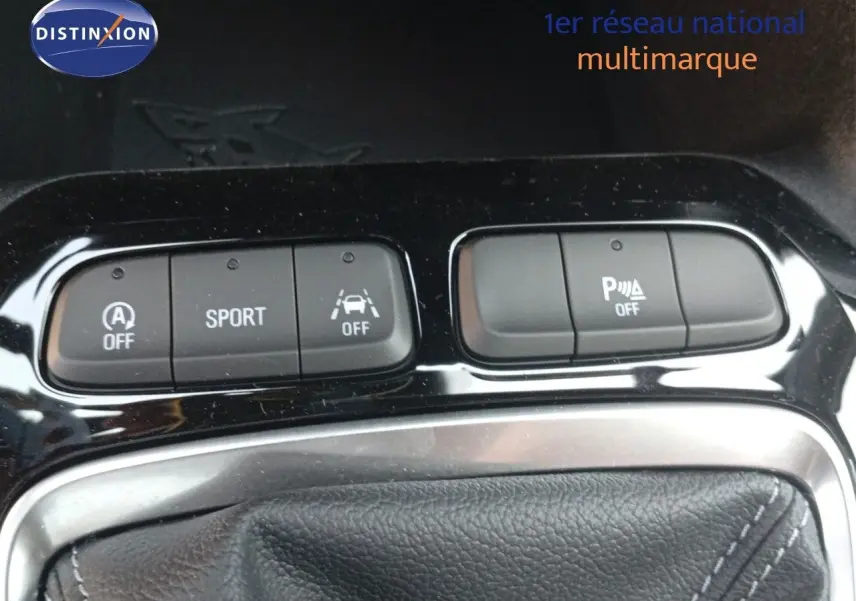 Gros plan sur les commandes de mode sport et assistance au stationnement de l’Opel Corsa rouge Kardio métal toit noir 2023.