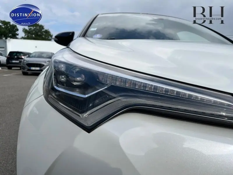 Gros plan sur le phare avant gauche du Toyota C-HR blanc nacré bi-ton, soulignant son design LED moderne.