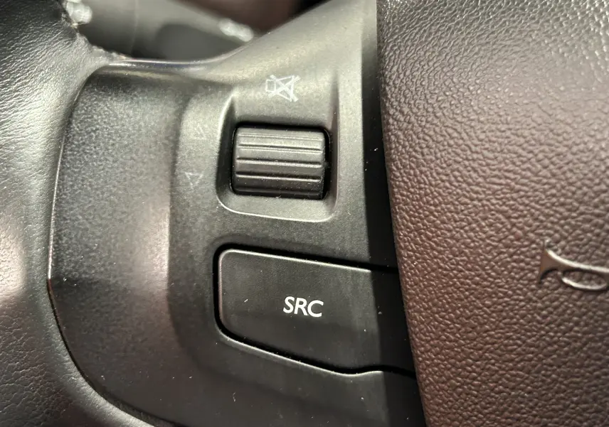 Gros plan sur les commandes noires du volant en cuir marron d'une Peugeot 2008 VTi 82 Allure blanche de 2014.