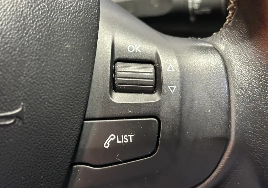 Gros plan sur les commandes au volant noir d'une Peugeot 2008 blanc essence, version Allure 2014.