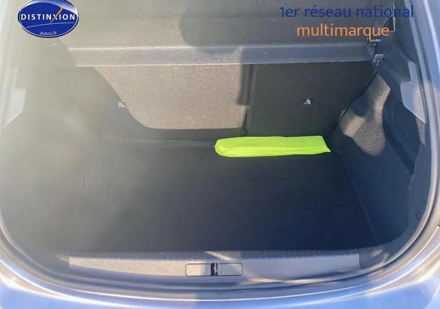 Coffre ouvert de la Peugeot 208 gris Artense, montrant un intérieur spacieux avec un triangle de signalisation jaune.