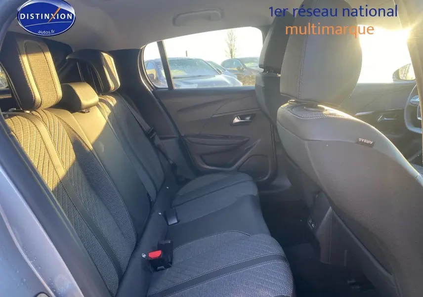 Vue intérieure côté gauche montrant la banquette arrière en tissu gris avec appuie-têtes, lumière naturelle entrant par la fenêtre.