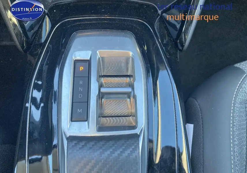 Vue rapprochée du levier de vitesses automatique et des commandes centrales en finition noire brillante dans une Peugeot 208 gris artense.