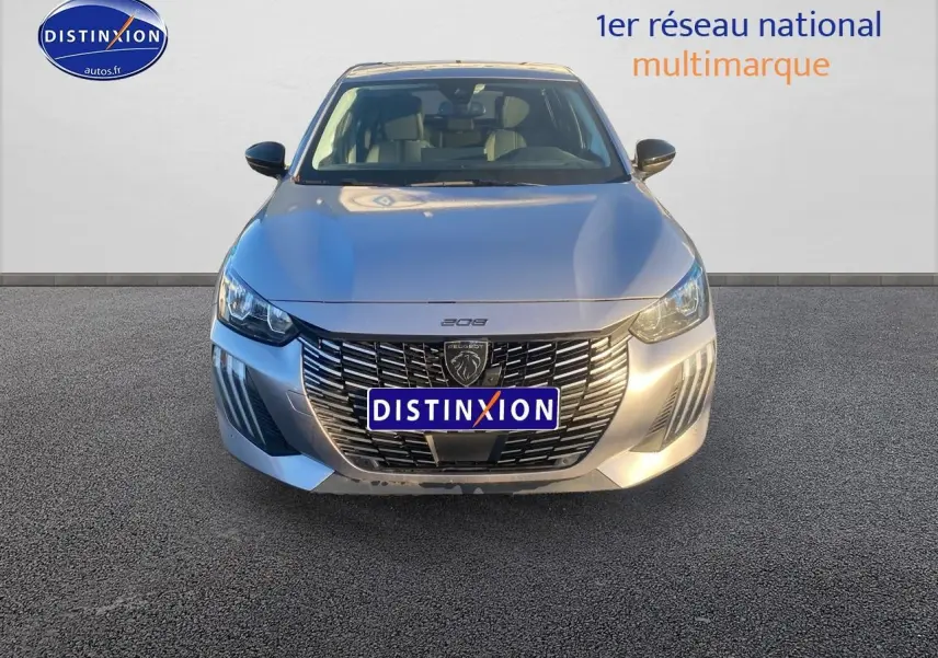 Vue frontale d'une Peugeot 208 gris artense avec calandre noire et phares LED allumés.