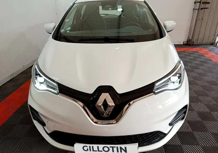 Vue avant d'une Renault ZOE Business R110 blanche avec phares LED allumés dans un garage.