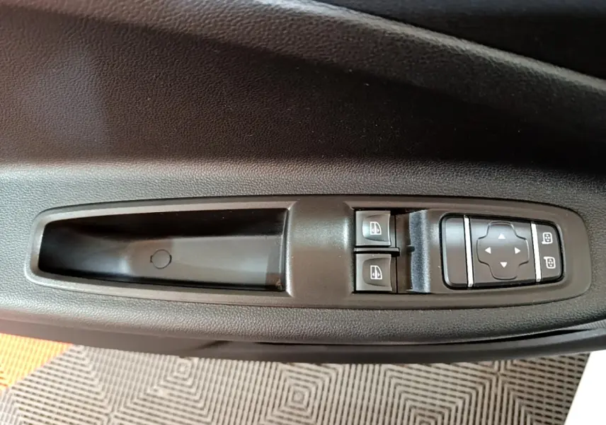 Vue rapprochée des commandes de lève-vitres et réglage des rétroviseurs sur la porte côté conducteur d'une Renault ZOE blanche.