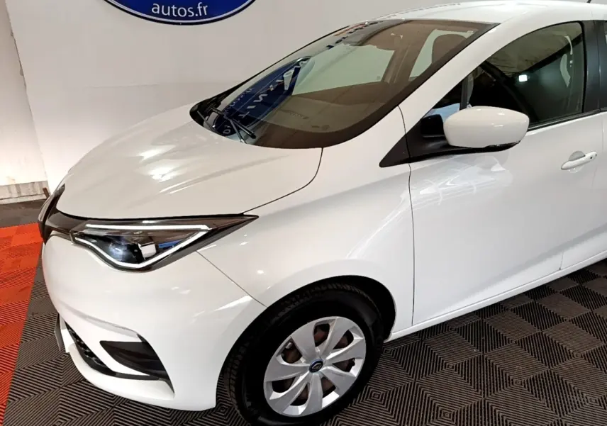 Vue 3/4 avant droit d'une Renault ZOE Business R110 blanche, mettant en valeur ses phares LED et jantes alliage.