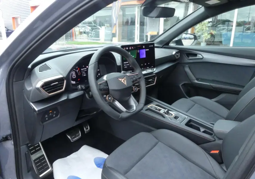 Intérieur avant droit du CUPRA Formentor 2025 gris Graphène, sièges suédine noire et volant cuir avec logo Cupra cuivré.