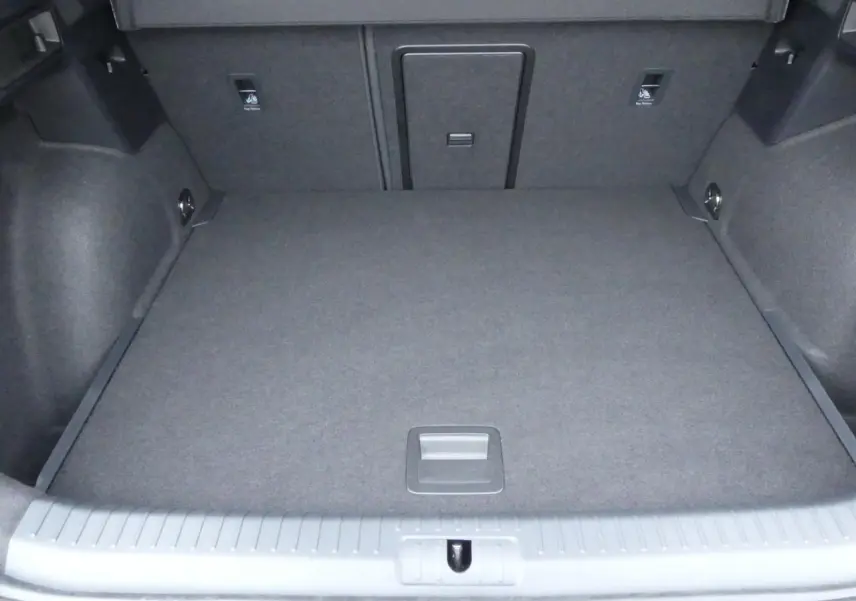 Coffre spacieux vu de face, revêtement gris foncé, avec trappe centrale et ancrages visibles.