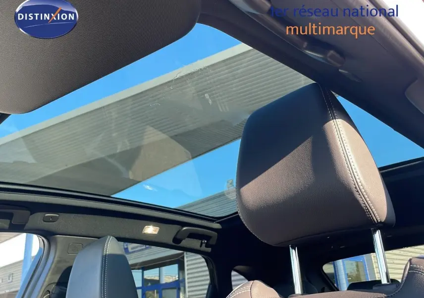 Vue intérieure sur les sièges avant en cuir noir et toit panoramique ouvrant du Nissan Qashqai blanc nacré 2025.