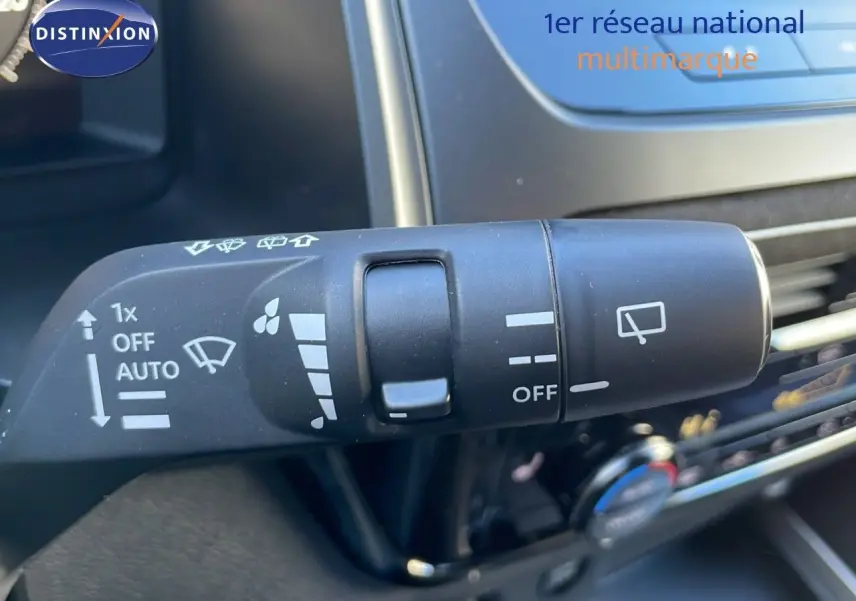 Gros plan sur la commande d’essuie-glace du Nissan Qashqai blanc nacré 2025, intérieur avec écran tactile visible.