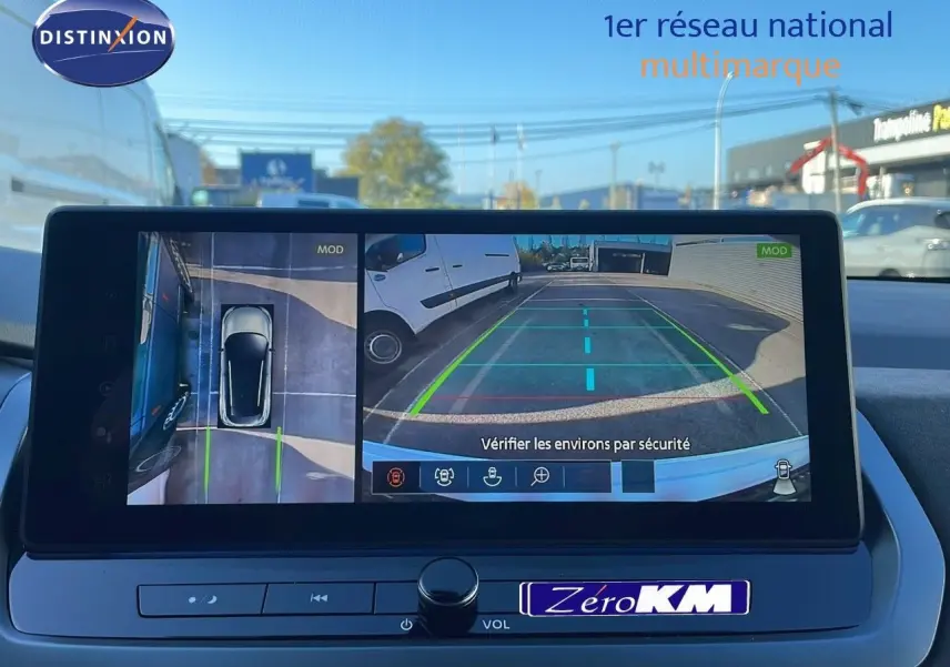 Écran intérieur du Nissan Qashqai 2025 montrant la caméra de recul avec vue arrière et vue aérienne du véhicule blanc nacré toit noir.