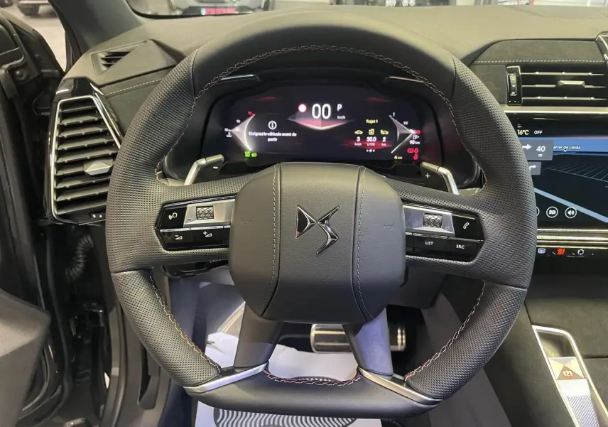 Vue intérieure centrée sur le volant DS en cuir perforé avec surpiqûres Carmin et Or du DS7 Crossback gris titanium.