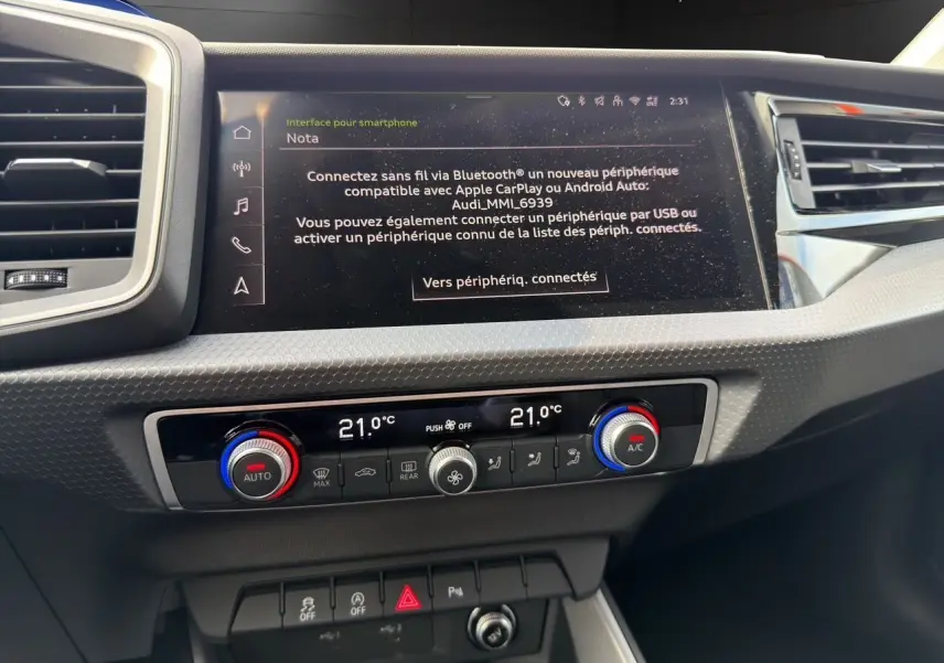Vue rapprochée de la console centrale de l'Audi A1 Sportback 2025, écran tactile et commandes climatisation à 21°C.