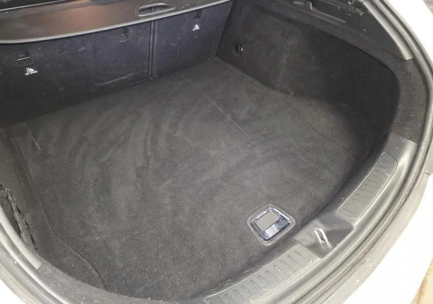 Coffre ouvert d'une Mercedes Classe CLA Shooting Brake gris, vue plongeante sur l'espace de chargement vide.