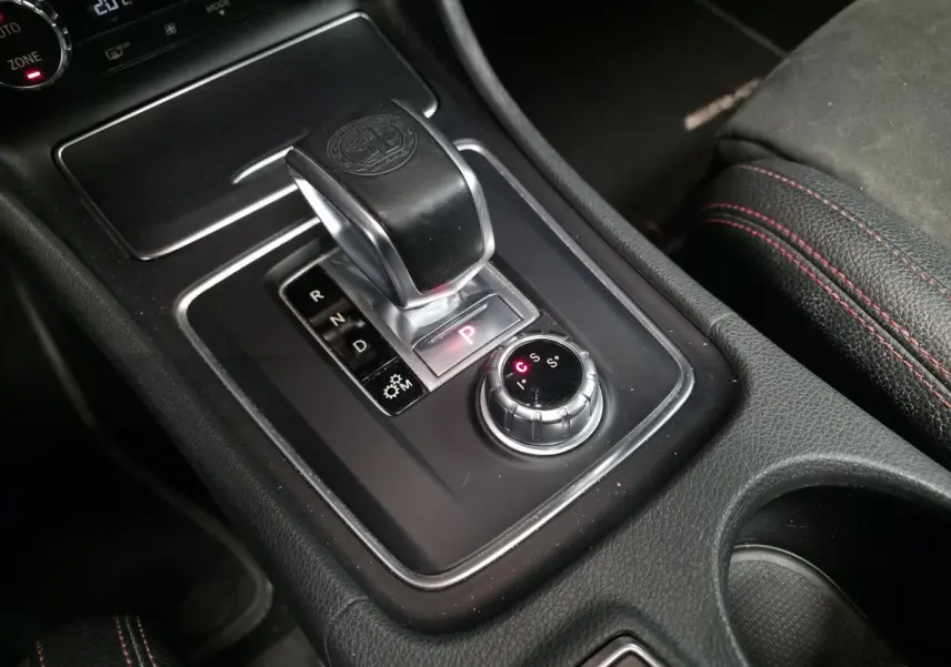 Gros plan sur la console centrale noire avec levier de vitesse automatique et sélecteur de modes AMG rouge et noir.