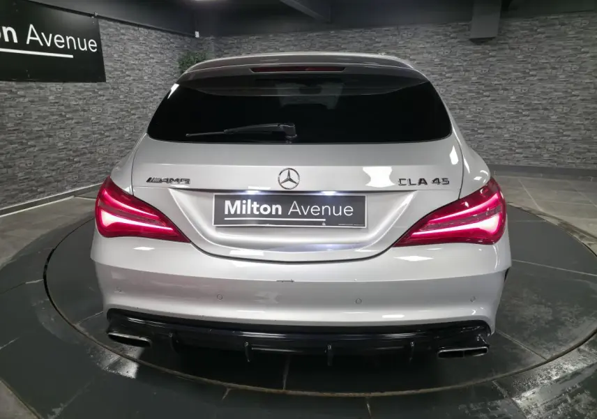 Vue arrière d'une Mercedes CLA 45 AMG gris métallisé avec feux LED allumés et double sortie d'échappement chromée.