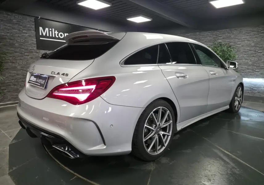 Mercedes CLA 45 Shooting Brake gris vue 3/4 arrière droit, feux arrière allumés et jantes AMG 18 pouces visibles.