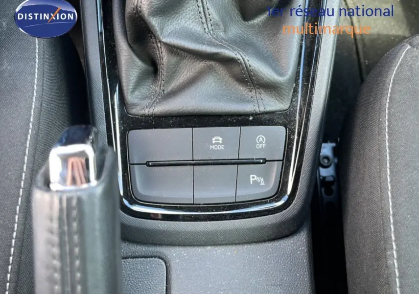 Gros plan sur la console centrale noire de la Skoda Scala 2025, montrant le levier de frein à main et les boutons de mode et assistance.