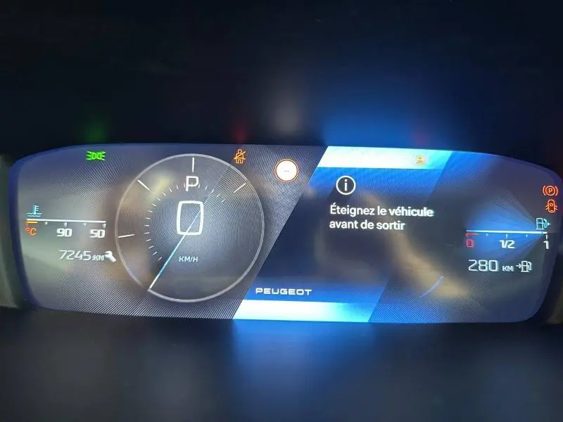 Tableau de bord numérique de Peugeot 308 2024 affichant vitesse à 0 km/h et message d'arrêt avant sortie.