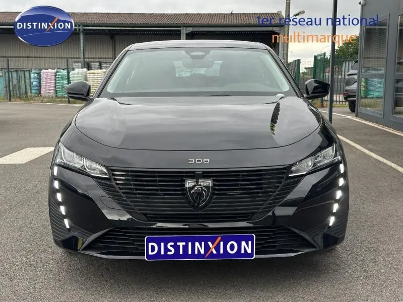 Vue frontale d'une Peugeot 308 2024 noire Perla Nera avec calandre noire et feux LED verticaux allumés.