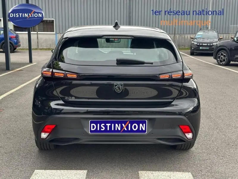 Vue arrière d'une Peugeot 308 2024 noire Perla Nera avec feux LED caractéristiques et logo lion central.
