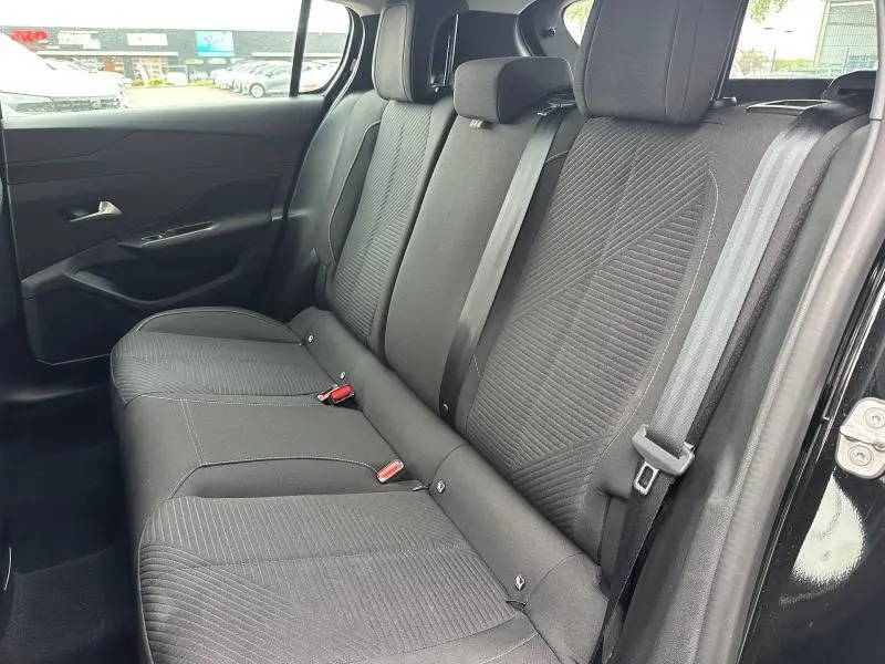 Vue intérieure côté droit des sièges arrière noirs de la Peugeot 308 2024 avec ceintures et textures tissu visibles.