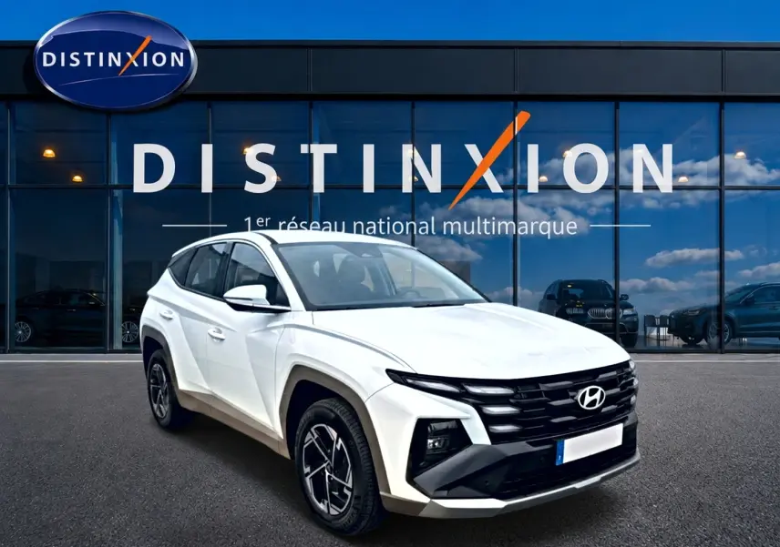 Hyundai Tucson blanc en 3/4 avant droit, avec calandre noire et jantes alliage 17 pouces devant showroom Distinxion.