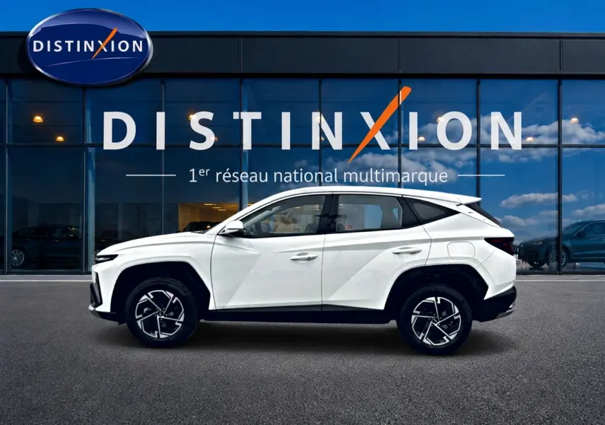 Hyundai Tucson blanc en profil droit devant une vitrine avec logo Distinxion, jantes alliage 17 pouces visibles.
