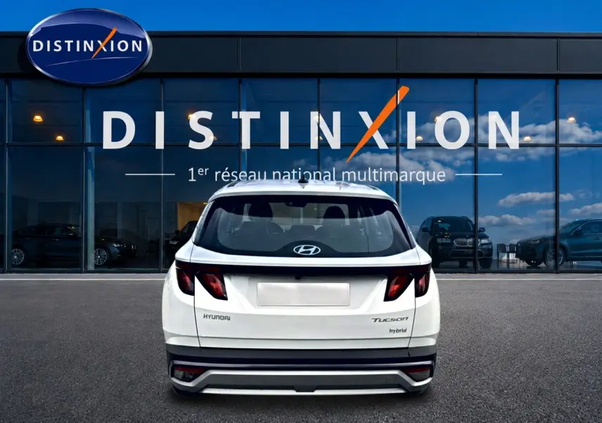 Vue arrière d'un Hyundai Tucson blanc hybride 2026, avec feux arrière sombres et logo Hyundai visible.