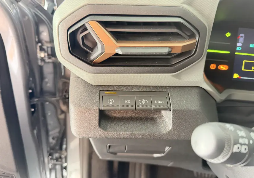 Détail intérieur du tableau de bord du Dacia Duster Hybrid 155 Extreme 2026, avec aérateur brun cuivré et boutons de modes de conduite.