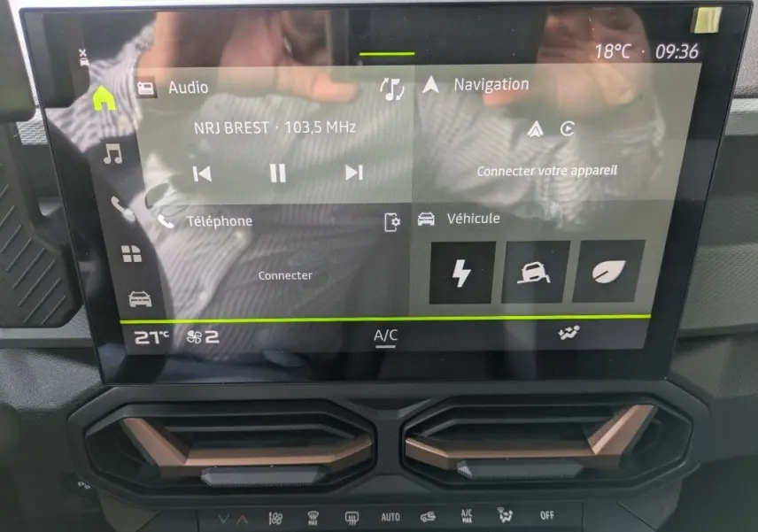Écran tactile 10,1'' du tableau de bord du Dacia Duster Hybrid 155 Extreme avec commandes climatisation et détails brun cuivré.