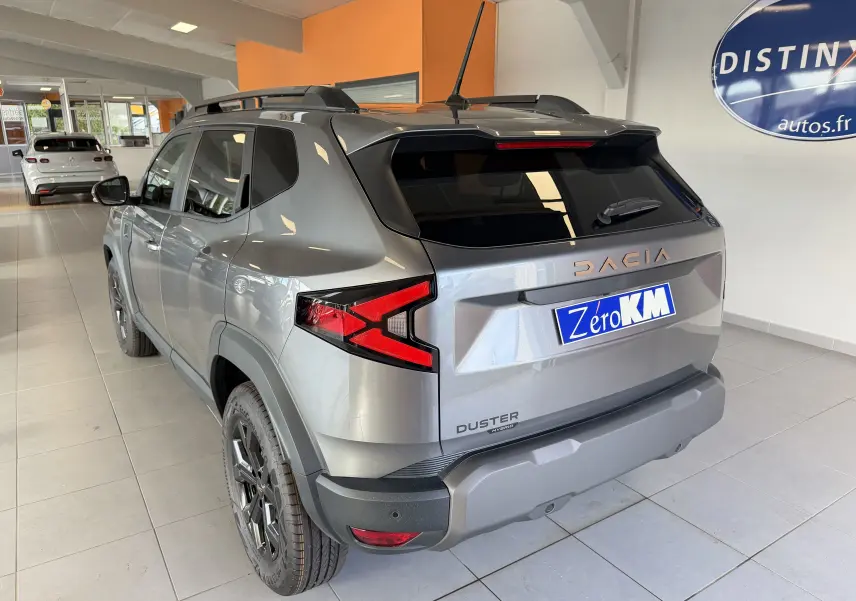 Vue 3/4 arrière droite du Dacia Duster Hybrid 155 Extreme gris schiste avec jantes noires et vitres surteintées en showroom.