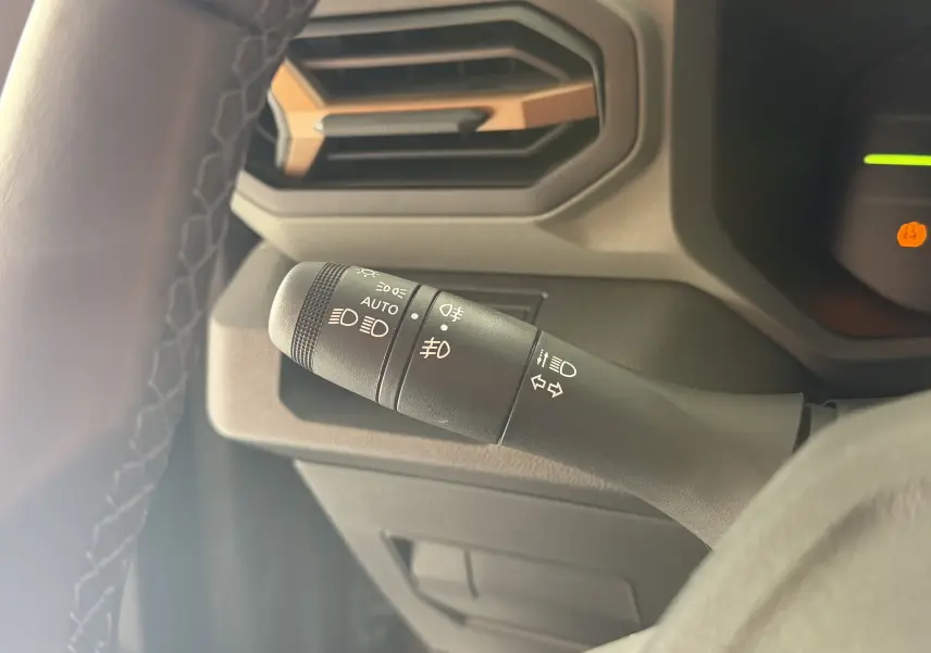 Gros plan sur la commande des feux à gauche du volant dans l’habitacle du Dacia Duster Hybrid 155 Extreme 2026.