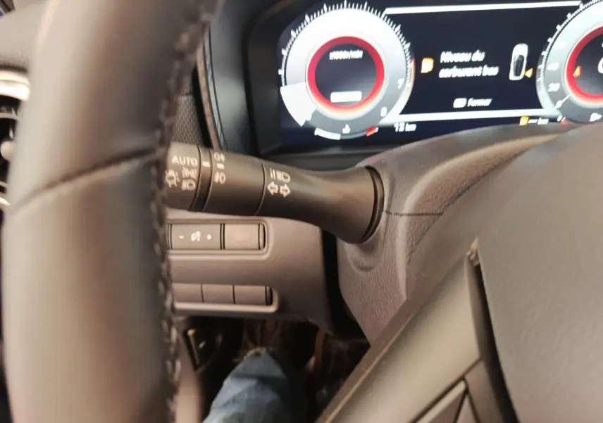 Vue rapprochée du tableau de bord et du volant noir du Nissan Juke 2025, affichage numérique et commandes au volant visibles.