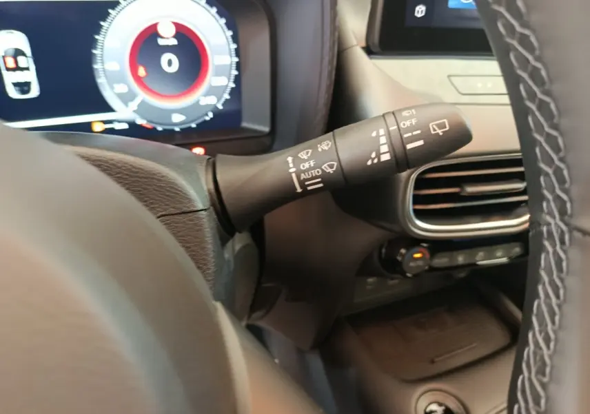 Gros plan sur la manette d’essuie-glace à gauche du volant dans l’habitacle du Nissan Juke bleu 2025.