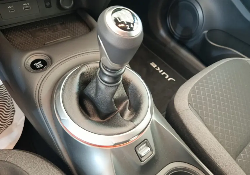 Vue rapprochée de la console centrale intérieure du Nissan Juke bleu 2025, avec levier de vitesse manuel et bouton Start/Stop.